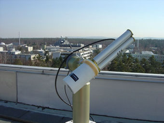 An image of the sun photometer that is set up on the roof of the main administration building of the Karlsruhe Institute of Technology (KIT). In the background, you can see the radome of the precipitation radar on the roof of the Institute for Meteorology and Climate Research.