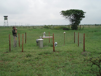 The sun photometer is pointing to the sky during the routine daily sampling of  the atmosphere. Proximity to the industrial area of Nairobi allows for systematic monitoring of aerosols and pollution in this fast and expanding metropolis in East Africa. The site is fenced in to protect instruments from wildlife intrusions and damage.